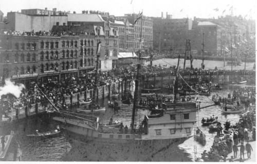 Market Slip - on the morning of June 24th, 1904. The city was celebrating the 300th year anniversary of Samuel de Champlain's arrival in the Saint John harbour. Note the replica of Champlain's ship "L'ACADIE". Also, note the Labourers Bell, which is being occupied by some onlookers. (Heritage Resources Photo)