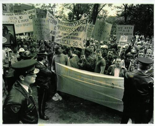 On 22nd of September 1976 Prime Minister Pierre Trudeau came to Saint John to speak to a noon-hour business crowd at the Admiral Beatty Hotel. Five to Six hundred union members showed up in front of the hotel to protest his government's wage control program. Note the hand painted banner of the Sugar Refinery workers, " Roll Back to Ottawa TRUDEAU--You Make Us Sick."